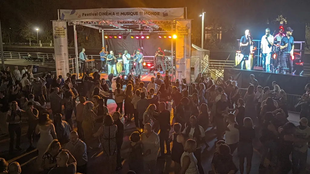 Spectacle extérieur en soirée, groupe sur scène et foule qui danse — Festival Cinéma et Musique du Monde, Saint-Jean-sur-Richelieu (en collaboration avec la SPEC).