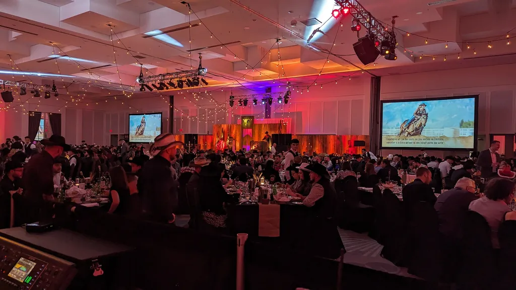 Grande salle de banquet corporatif à thème western, écrans géants et éclairage rouge et ambré — chef éclairagiste, événement corporatif de haut niveau, Laval.